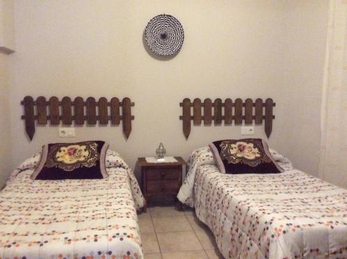 a bedroom with two beds and a clock on the wall at Apartamento Rural Castildetierra in Arguedas