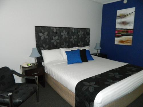 a bedroom with a large bed and a chair at Orana Windmill Motel in Gilgandra