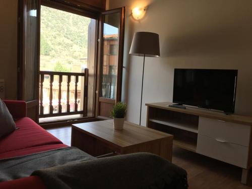 Una sala de estar con un sofá y un televisor de pantalla plana. en Apartamentos La Solana, en Potes