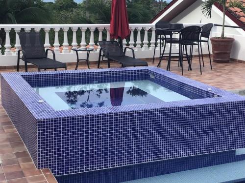 a tile swimming pool with chairs and a table at Hotel Los Cielos Del Caribe in Cahuita