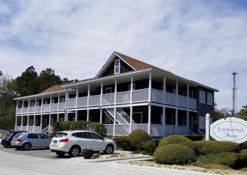 a large building with cars parked in a parking lot at Scarborough Inn in Manteo