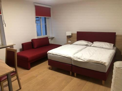 a bedroom with a bed and a red couch at Hotel & Gastropark Loemühle in Marl