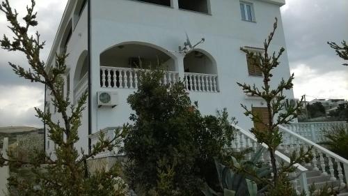 a white house with a balcony and some trees at Apartments Kuss in Novalja