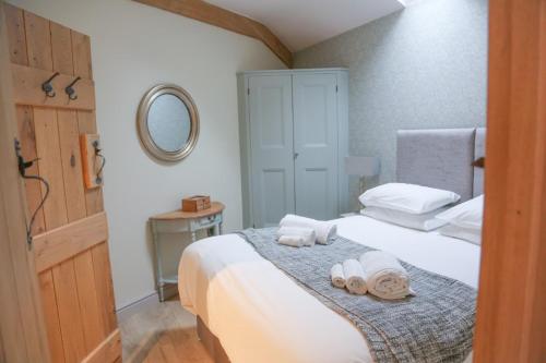 a bedroom with a bed with towels and a mirror at BARLEY - cosy stylish apartment - easy access to Bath and many nearby attractions in Box