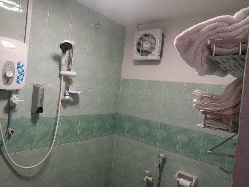 a bathroom with a shower with a fan and towels at Home Inn Hotel in Ipoh