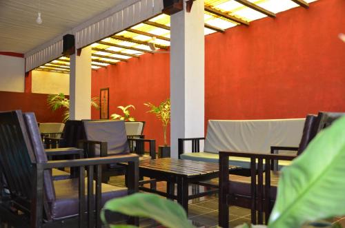 a patio with tables and chairs and a red wall at SAARA HOTEL in Mahajanga