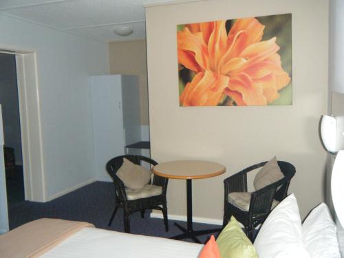 a hotel room with a table and chairs and a painting at Orana Windmill Motel in Gilgandra