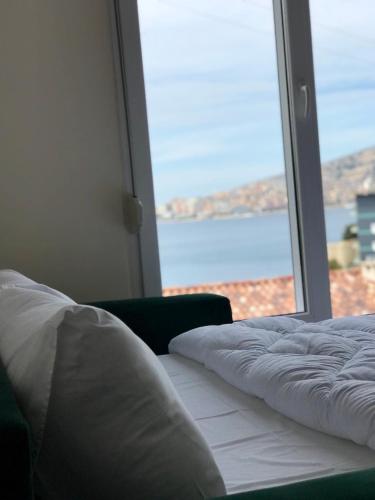 a bed with a view of the ocean through a window at Sunny Bay Apartments in Sarandë