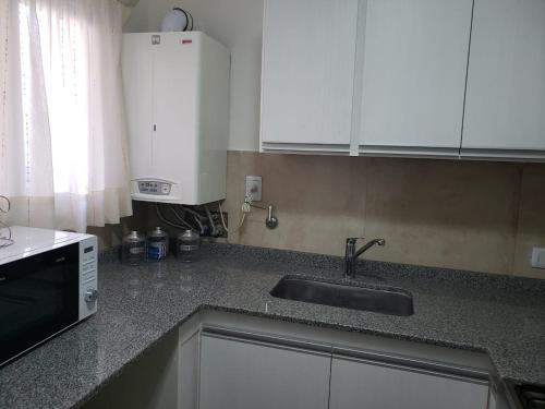 eine Küche mit Spüle und Mikrowelle in der Unterkunft Departamento Centrico in Villa María