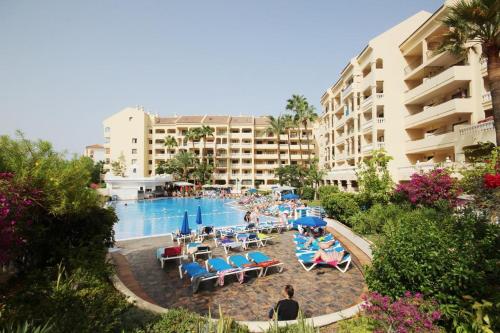 a swimming pool with chairs and people in a resort at castle harbour in Los Cristianos