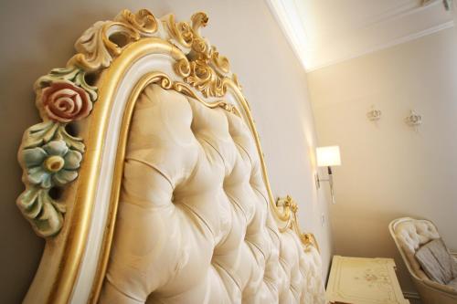 einen goldgerahmten Spiegel an einer Wand neben einem Bett in der Unterkunft Hotel Villa Margherita in Quercianella