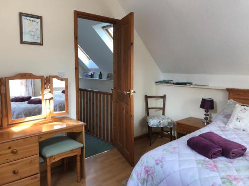 a bedroom with a bed and a desk and a mirror at Meadow Sweet Cottage in Okehampton