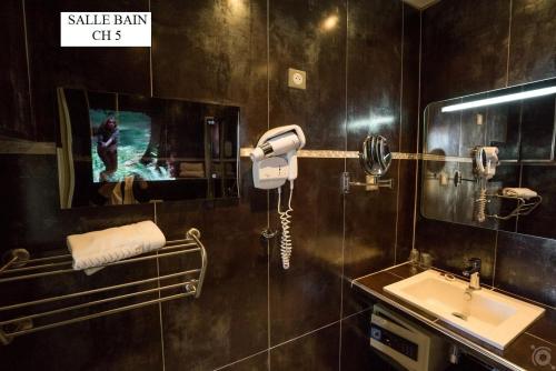 baño con lavabo y TV en la pared en Hotel Restaurant Bellevue, en Bormes-les-Mimosas