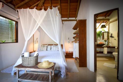 a bedroom with a canopy bed with a hat on a table at Biribandos Rooms by Trancoso House in Trancoso
