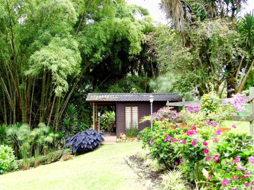 a small cabin in a garden with flowers at Gue Guatok in Salento