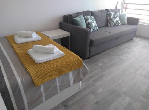 a living room with a couch and a table with towels at BSB Surf&Beach Apartment Salou in Salou