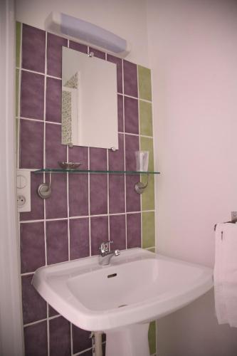 La salle de bains est pourvue d'un lavabo blanc et de carrelage pourpre. dans l'établissement Terrasses de l'Aven, à Orgnac-lʼAven