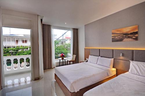 a bedroom with two beds and a large window at For You Hotel in Nha Trang