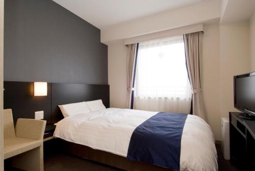 a hotel room with a bed and a window at Dormy Inn Premium Shimonoseki in Shimonoseki