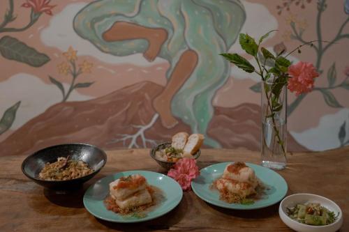 a table with plates of food and a vase with flowers at Dulan The Travel Bug Bistro Inn in Donghe