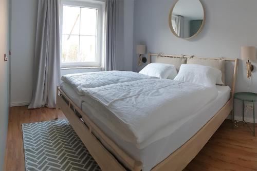ein großes Bett in einem Schlafzimmer mit einem Spiegel in der Unterkunft Ferienwohnung *Windstille* in Wittdün