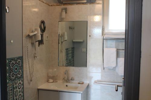 a bathroom with a sink and a shower with a mirror at Hotel La Peyrade in Cajarc