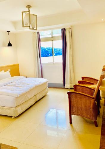 a bedroom with a bed and a chair and a window at Taihu Hotel Sun Moon Lake in Yuchi