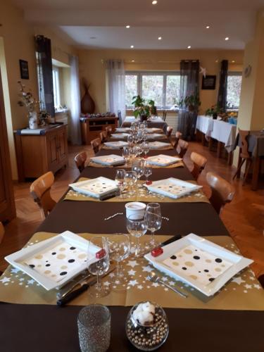 un comedor largo con una mesa larga con copas de vino en Chambre d'Hotes Le Saut de La Truite, en Orbey