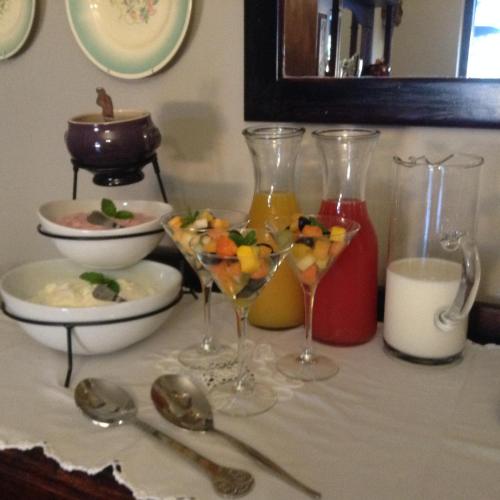 a table with two wine glasses and a bowl of fruit at Gerald's Gift Guest House in Addo