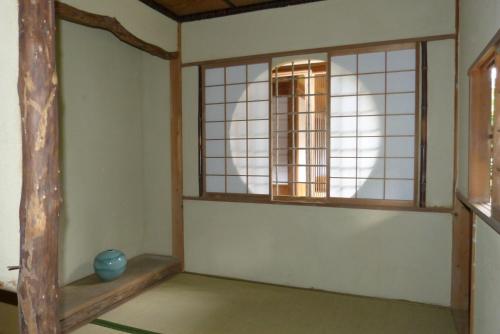 a room with two windows and a vase on the floor at Guesthouse Higashi Fujitatei in Shinonsen