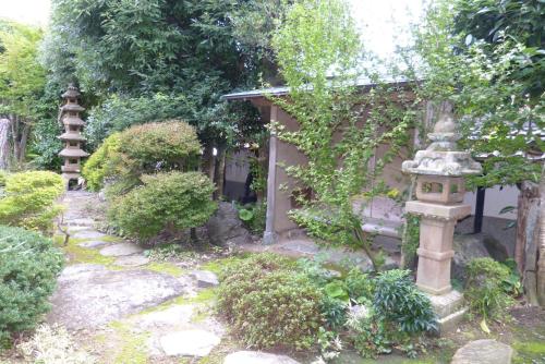 an asian garden with a bird cage and a bird house at Guesthouse Higashi Fujitatei in Shinonsen