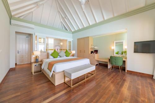 a bedroom with a bed and a desk and a television at Sun Siyam Olhuveli in South Male Atoll
