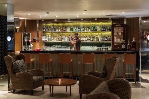 a man standing behind a bar with two chairs at The Park Navi Mumbai in Navi Mumbai