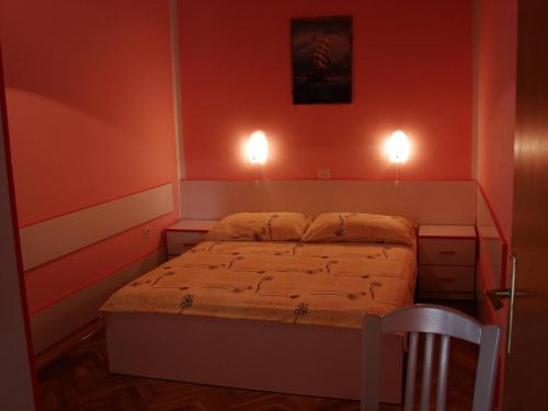a bedroom with a bed with two lights on the wall at Apartments Slavko in Supetarska Draga