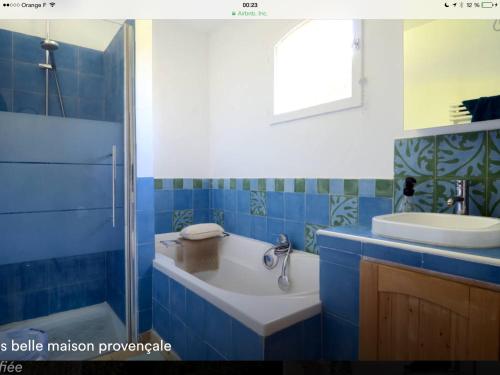 uma casa de banho azul com uma banheira e um lavatório em Lou Parpaillou em Éguilles