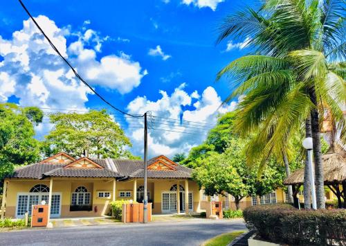 a house on a street with a palm tree at Rumbia Resort Villa Paka in Paka