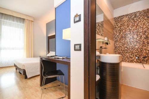 a hotel room with a desk and a bed and a bathroom at Hotel City in Desenzano del Garda