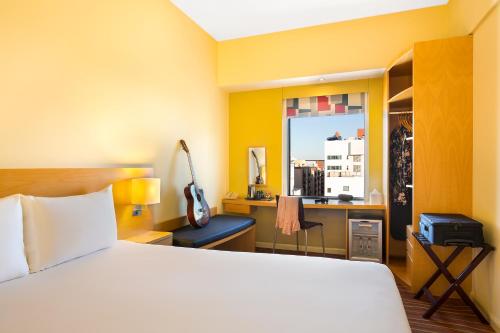 a bedroom with a bed and a desk and a window at Ibis Al Rigga in Dubai