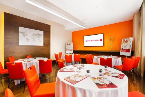 a restaurant with tables and orange chairs and a screen at ibis Dubai Al Rigga in Dubai
