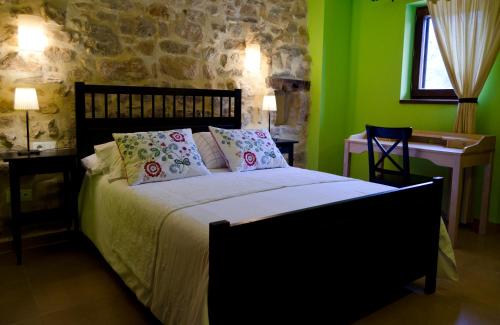 a bedroom with a bed with green walls and a desk at Apartamentos Playa Galizano in Galizano
