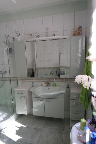 a white bathroom with a sink and a shower at Ferienwohnung "Hedwig" in Bad Saarow