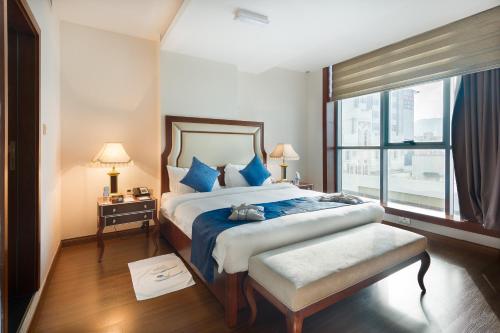 een slaapkamer met een groot bed en een groot raam bij Golden Tulip Headington in Muscat