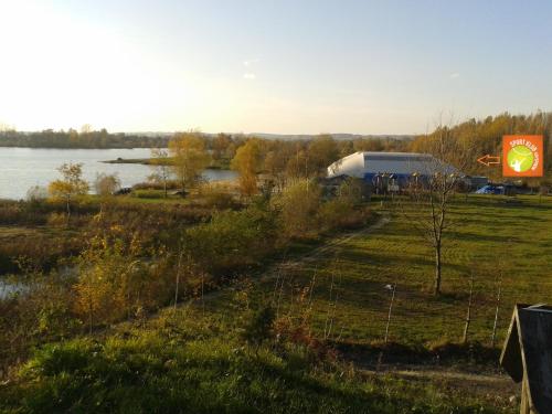 a view of a field with a building and a lake at Osada Kryspinów in Cholerzyn