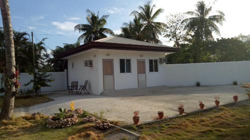 a small white house with a fence and palm trees at Kathleens Vacation Place in Moalboal