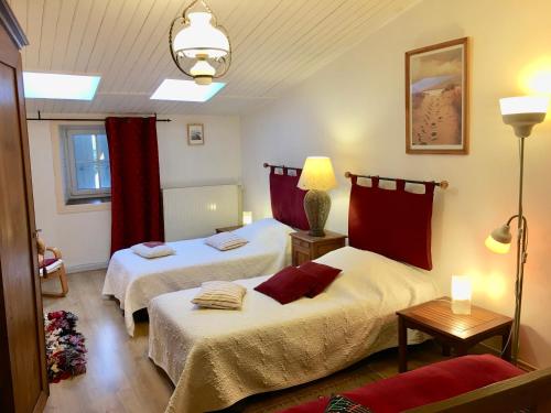2 camas en una habitación con cortinas rojas en Chambres d'Hôtes Le Logis du Port Paradis, en Nieulle-sur-Seudre