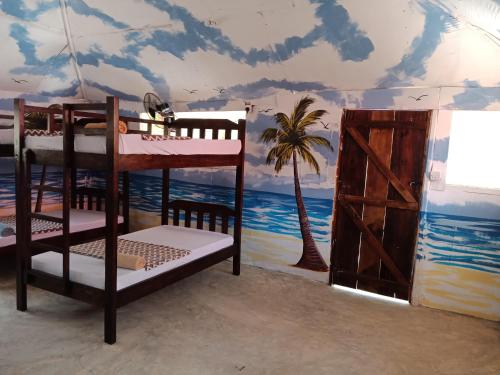 a room with bunk beds and a mural of the ocean at Soul Breeze Backpackers Diani in Diani Beach