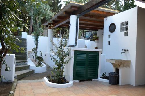 a white house with a green door and a sink at B&B Il Giardino Segreto in Stromboli