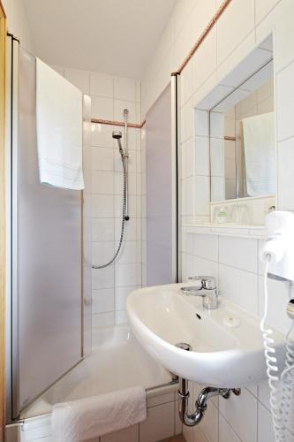 a white bathroom with a sink and a shower at Gästehaus Sonnenbichl in Fischbachau