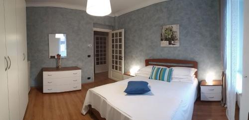 a bedroom with a white bed with a blue pillow on it at La Casa Gialla in Monforte dʼAlba