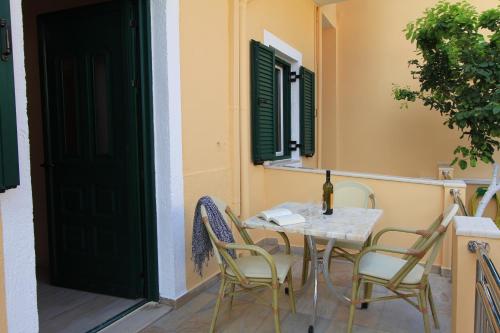 een tafel en stoelen op een balkon met een fles wijn bij George Studios in Vasiliki